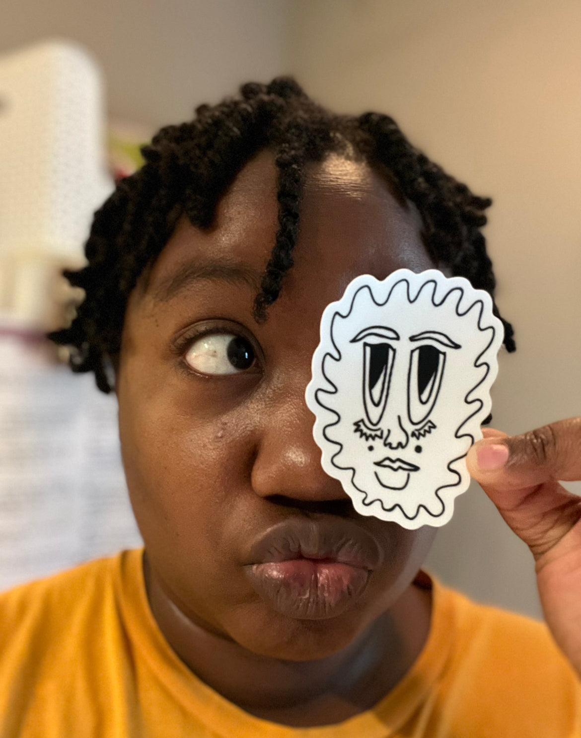 photo of the artist holding up their abstract art sticker depicting a floating face of a black person